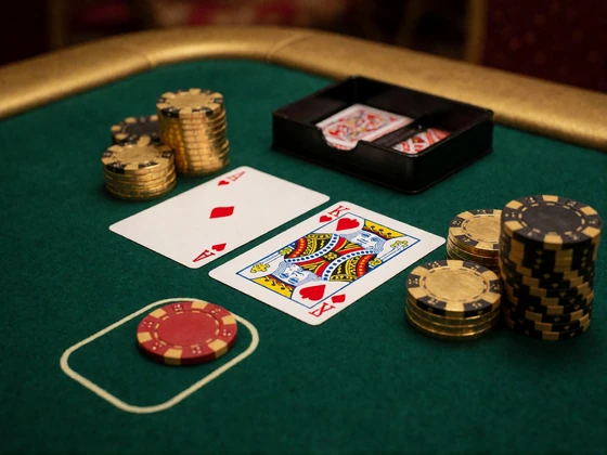 Blackjack-Tisch mit Ass und K&ouml;nig sowie Goldchips als Symbol f&uuml;r Jackpot-Spiele und Tischspiele im Online Casino